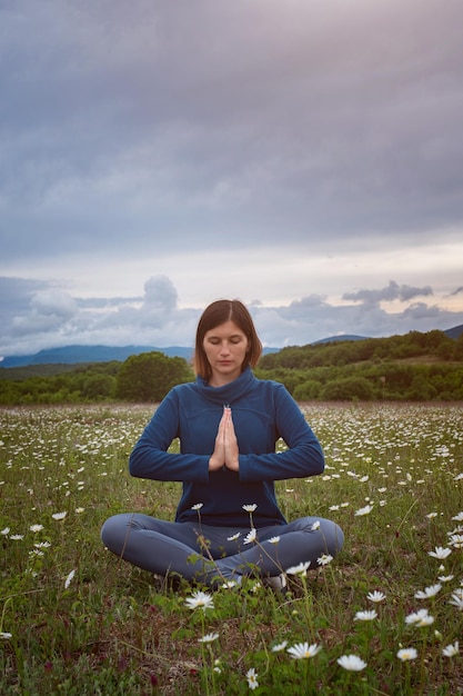 Una giovane donna che fa yoga nel campo