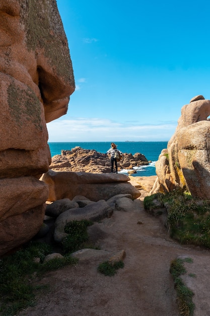 Una giovane donna che guarda il mare lungo il faro significa Ruz, porto di Ploumanach, nella città di Perros-Guirec, Cotes-d'Armor, nella Bretagna francese, Francia.