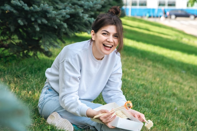 Una giovane donna che mangia sushi nel parco picnic in natura