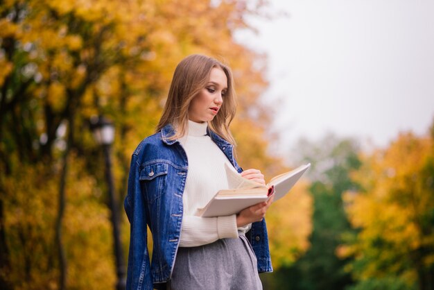 Una giovane donna che protegge dal virus corona quando cammina nel parco. Sfondo autunnale.