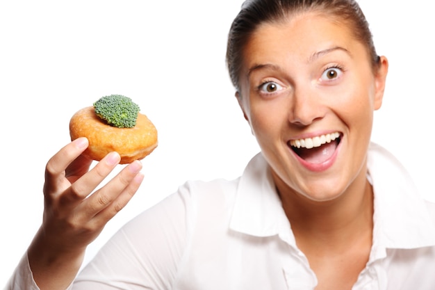 una giovane donna che trova un compromesso perfetto tra mangiare una ciambella e broccoli