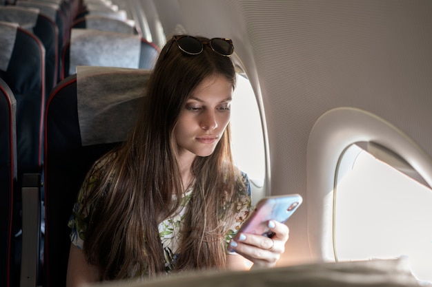 Una giovane donna che usa il telefono durante il volo in aereo