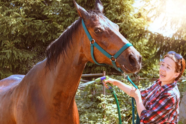 Una giovane donna chiama un cavallo all'obbedienza mentre si lava