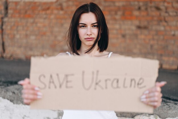 Una giovane donna chiede di salvare l'Ucraina con un cartello in mano Charity