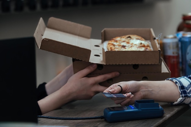 una giovane donna compra cibo pronto in scatole di cartone e paga tramite il terminal