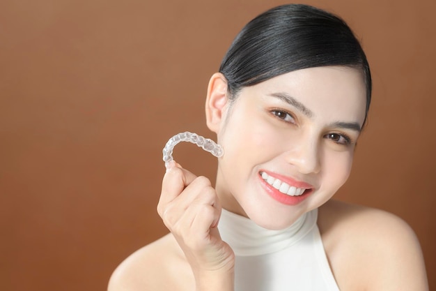 Una giovane donna con bei denti sta tenendo il concetto dentale sano Invisalign