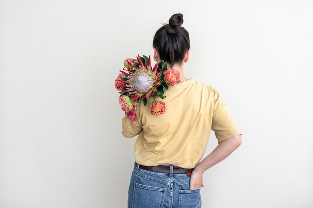 Una giovane donna con fiore protea su sfondo bianco