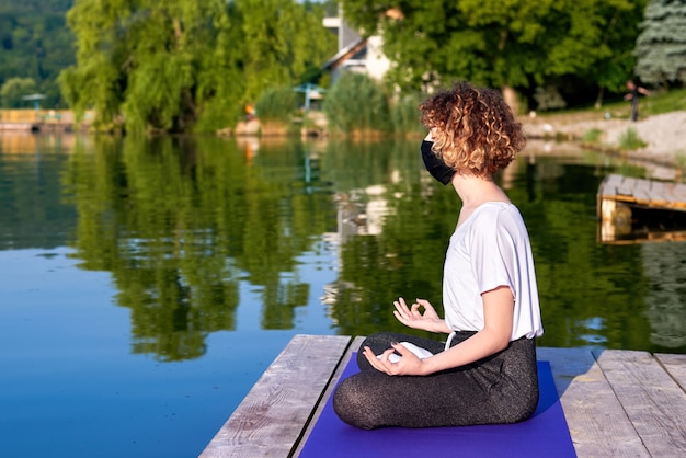 Una giovane donna con i capelli ricci che fa yoga all'esterno