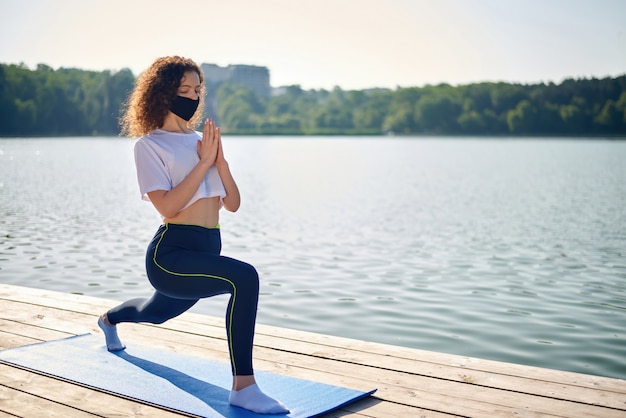 Una giovane donna con i capelli ricci che fa yoga all'esterno