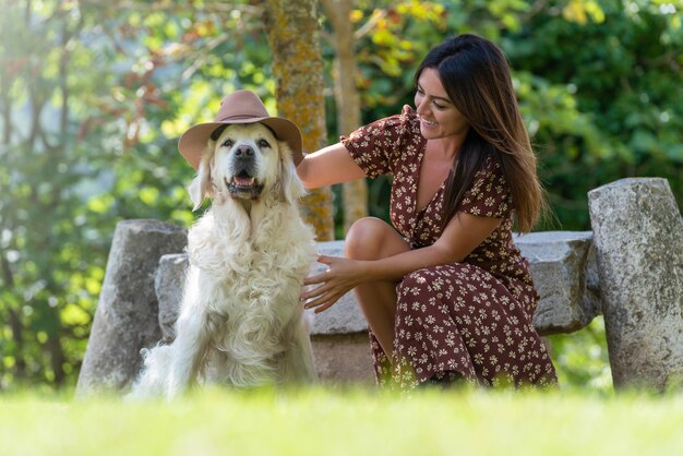 Una giovane donna con il suo cane bianco Ha messo un cappello sul cane Il cane sta guardando la telecamera