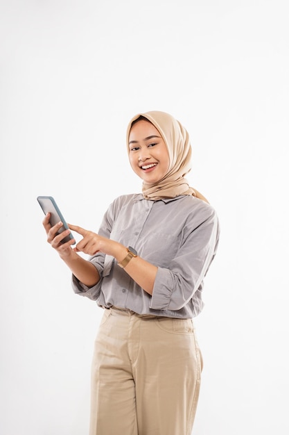 Una giovane donna con l'hijab in piedi e che punta sul suo telefono