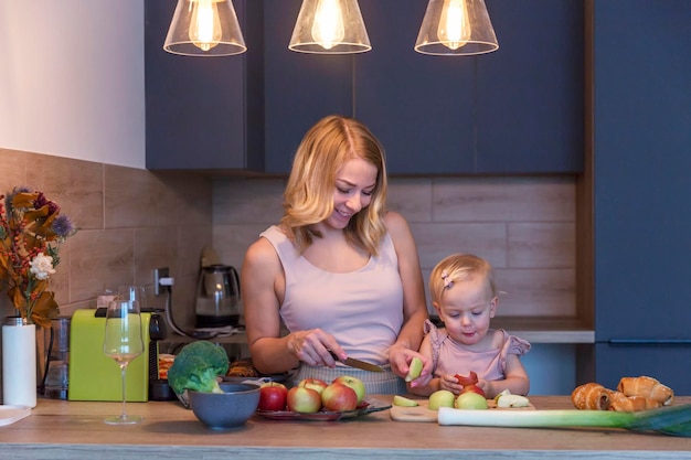 Una giovane donna con la sua piccola figlia sta cucinando in cucina Bella bionda sorridente insegna a un bambino Amore e tenerezza