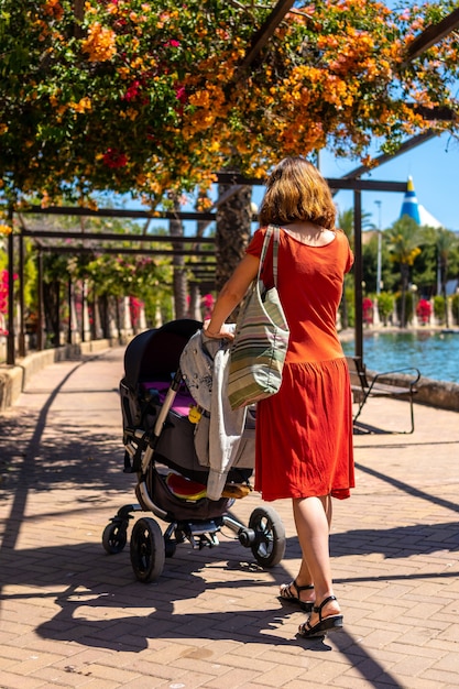 Una giovane donna con suo figlio in macchina a piedi attraverso il Parque de las Naciones nella città di Torrevieja, Alicante, Mar Mediterraneo