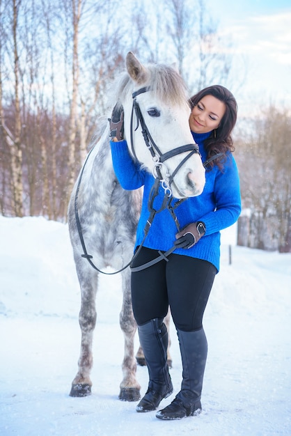 Una giovane donna con un bel cavallo bianco invernale