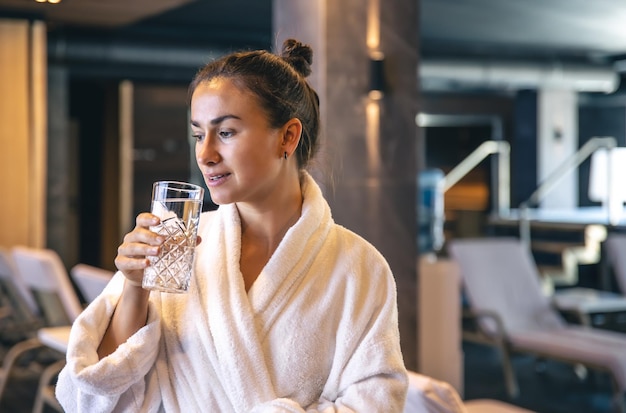 Una giovane donna con un bicchiere d'acqua dopo la sauna sta riposando