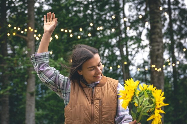 Una giovane donna con un bouquet di girasoli su uno sfondo sfocato in natura