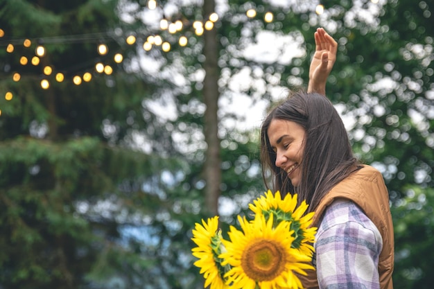 Una giovane donna con un bouquet di girasoli su uno sfondo sfocato in natura