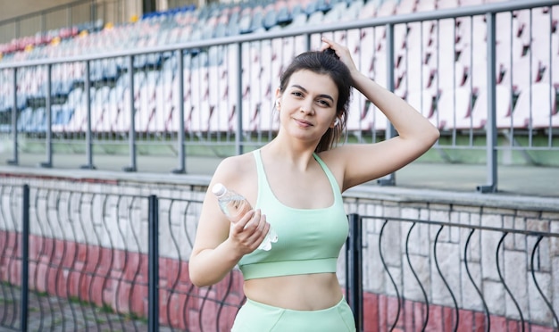 Una giovane donna con una bottiglia d'acqua in allenamento allo stadio