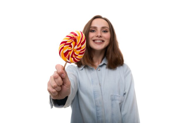 Una giovane donna con una camicia di jeans tiene in mano un lecca-lecca colorato