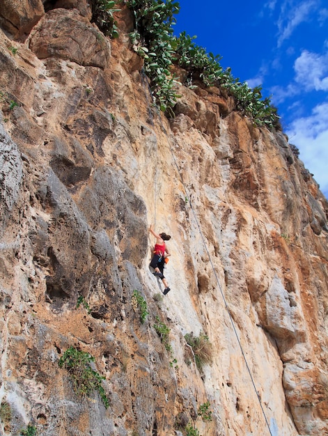 Una giovane donna con una corda impegnata negli sport di arrampicata su roccia.