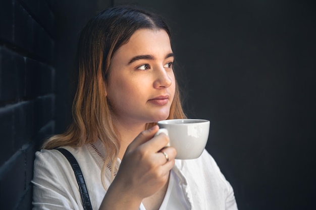 Una giovane donna con una tazza di caffè all'interno di un caffè nero