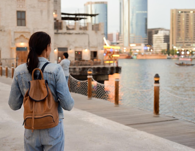 Una giovane donna con uno zaino sulla schiena ammira il fiume nella vecchia Dubai