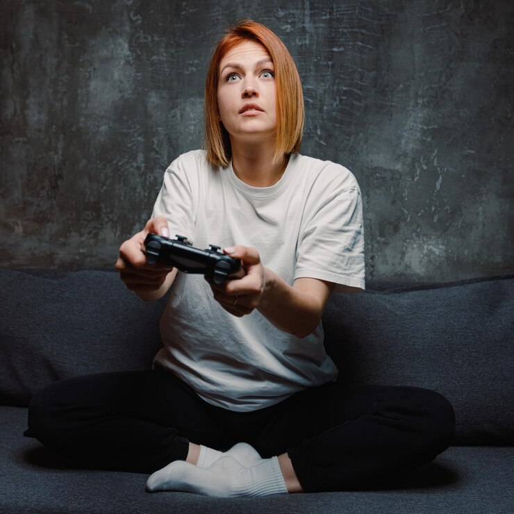 Una giovane donna concentrata che tiene in mano un joystick e gioca a un gioco online a casa