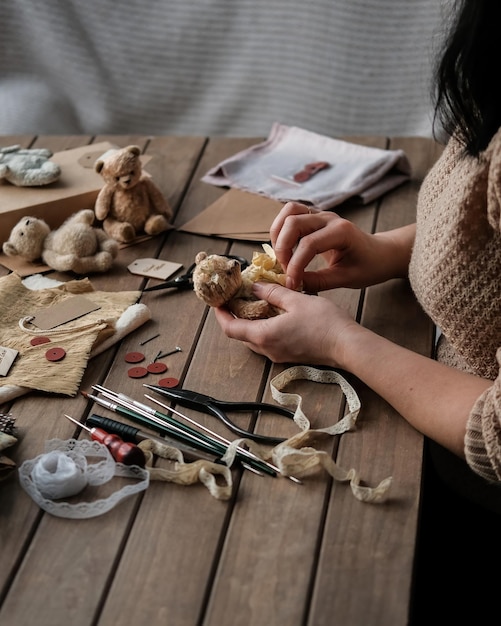 Una giovane donna cuce un orsacchiotto hobby