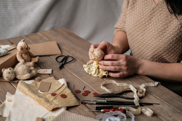 Una giovane donna cuce un orsacchiotto Processo di realizzazione di un giocattolo vintage