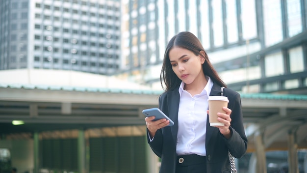 Una giovane donna d'affari che indossa un abito nero sta usando smart phone