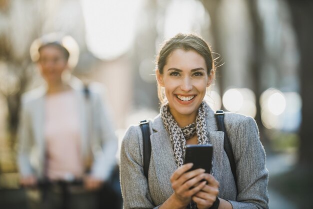 Una giovane donna d'affari che usa lo smartphone mentre va al lavoro.
