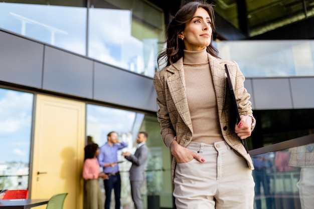 Una giovane donna d'affari fiduciosa che cammina con scopo in un moderno complesso di uffici durante il giorno