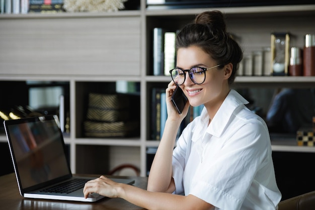 Una giovane donna d'affari sta parlando con lo smartphone nel suo ufficio