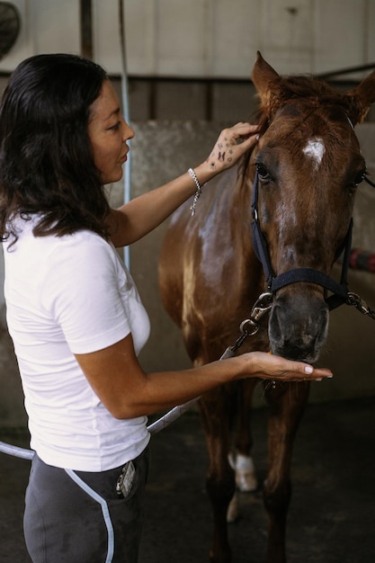 Una giovane donna dà da mangiare le carote a un cavallo.