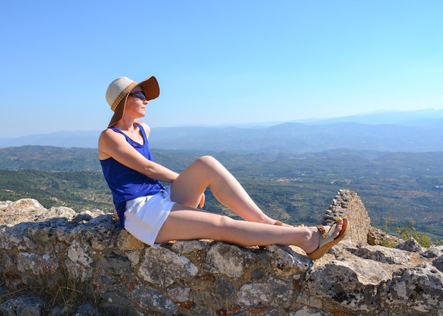 Una giovane donna dai capelli rossi con un cappello sta prendendo il sole nel Peloponneso in Grecia