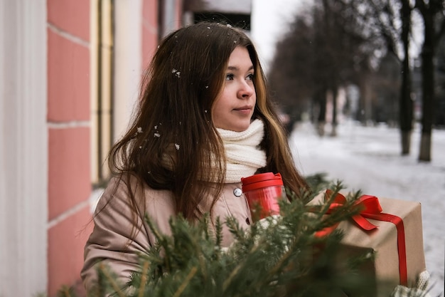 Una giovane donna dall'aspetto sognante beve il caffè e tiene in mano un regalo