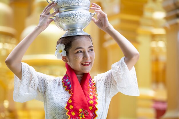 Una giovane donna del Myanmar in un tradizionale gesto di benvenuto con la pagoda Shwedagon