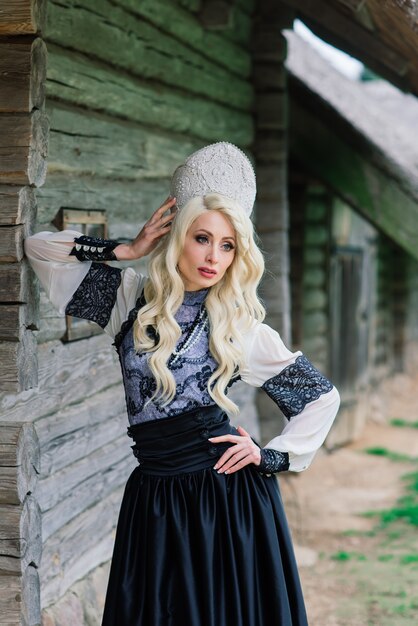 Una giovane donna di aspetto slavo con corona, kokoshnik su MidSummer, villaggio, fattoria