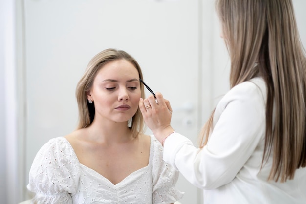 una giovane donna durante la procedura di mappatura delle sopracciglia da parte di un visagista professionista