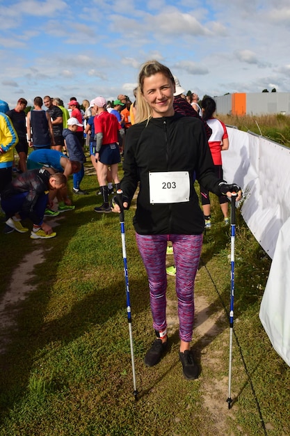 Una giovane donna e altri atleti di nordic walking iniziano all'inizio della competizione