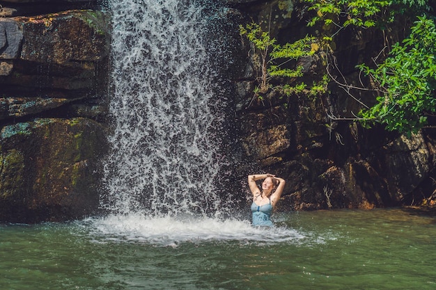 Una giovane donna è in piedi in una cascata.