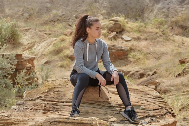 Una giovane donna è seduta su una roccia in una zona sabbiosa