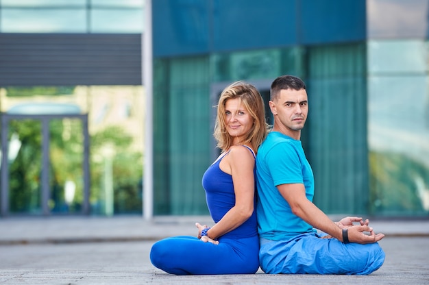 Una giovane donna e un uomo attraenti che fanno yoga all'aperto.