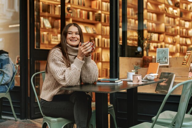 Una giovane donna elegante che beve caffè al caffè