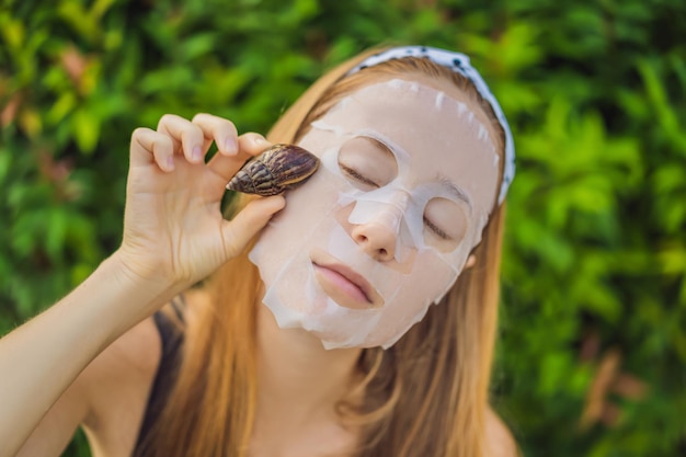 Una giovane donna fa una maschera facciale con muco di lumaca Lumaca che striscia su una maschera facciale