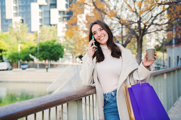 Una giovane donna felice che chiama dallo smartphone dopo lo shopping Signora isolata che parla e parla