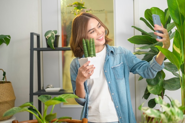 Una giovane donna felice che si fa selfie con le sue piante e fa una videochiamata a casa