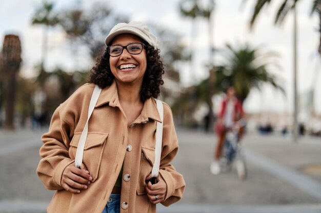 Una giovane donna felice e alla moda sta camminando per la strada in centro.