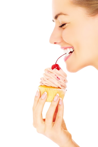 una giovane donna felice in posa con un cupcake su sfondo bianco