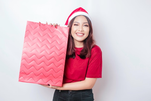 Una giovane donna felice indossa il cappello di Babbo Natale e tiene in mano i regali di Natale